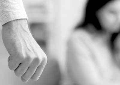 A man's fist in the foreground with a blurred pic of a woman and child in the background